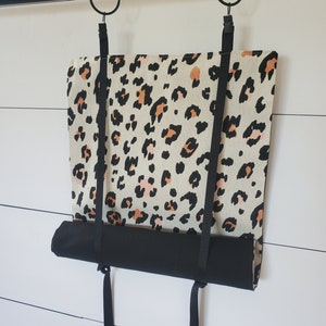 Op de afbeelding: Een zwart-witte luipaardprint stoffen rolgordijn met zwarte banden en een zwarte rol. Het gordijn hangt aan een zwarte stang.