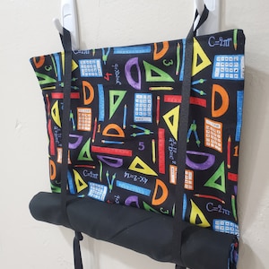 May include: A black fabric roll-up storage bag with black straps. The bag is printed with colorful math and geometry symbols, including protractors, rulers, compasses, calculators, and triangles. The text "C=2πr" is printed on the bag.