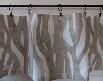 May include: A set of three valances with a brown and white abstract pattern. The valances are hung on a black curtain rod with black clips.