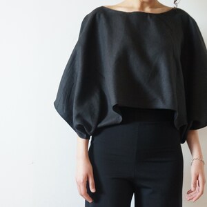 May include: A black, loose-fitting, cropped top with long, gathered sleeves.