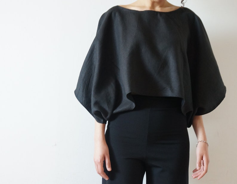 May include: A black, loose-fitting, cropped top with long, gathered sleeves.