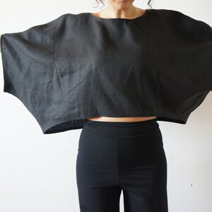 May include: A black linen top with a wide, flowing silhouette. The top has a relaxed fit and a cropped length.