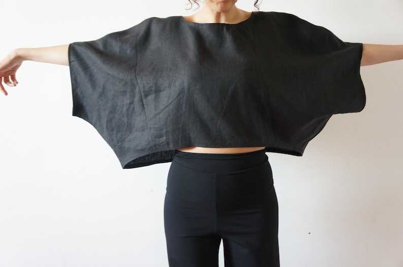May include: A black linen top with a wide, flowing silhouette. The top has a relaxed fit and a cropped length.