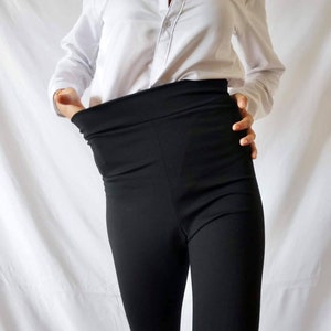 Puede incluir: Una camisa blanca abotonada con un pantal&oacute;n negro de cintura alta.