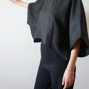 May include: A black linen top with a wide, flowing silhouette and short sleeves. The top is cropped and has a relaxed fit.