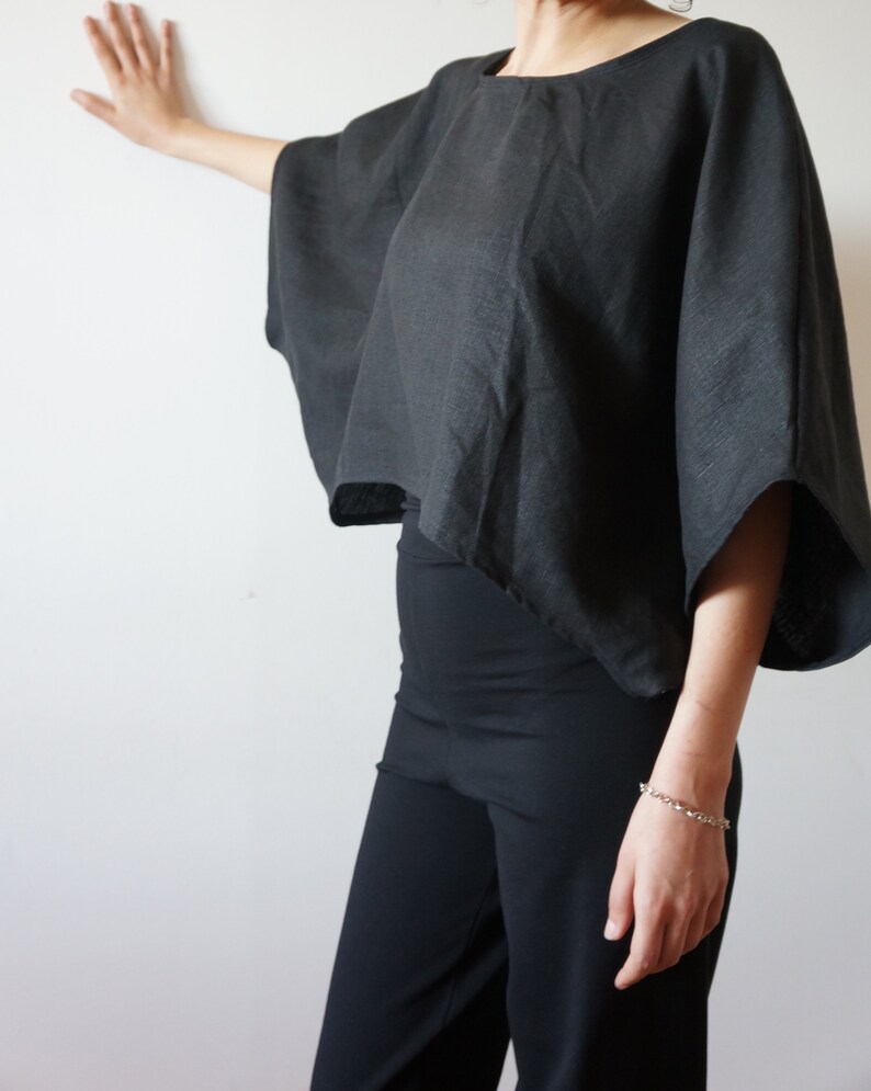 May include: A black linen top with a wide, flowing silhouette and short sleeves. The top is cropped and has a relaxed fit.