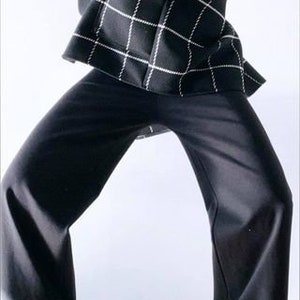 May include: A black and white checkered blazer and black pants. The blazer has a grid pattern with white lines on a black background. The pants are wide-legged and black. The outfit is a modern, stylish ensemble.