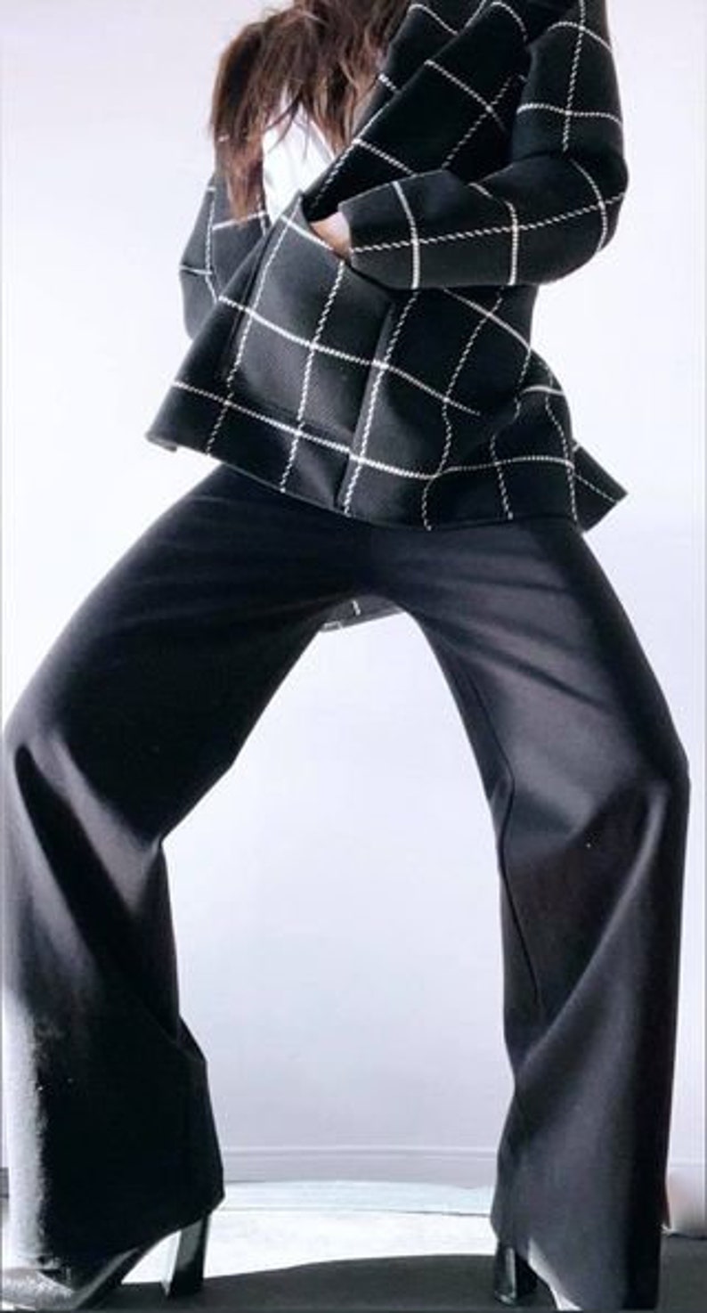 May include: A black and white checkered blazer and black pants. The blazer has a grid pattern with white lines on a black background. The pants are wide-legged and black. The outfit is a modern, stylish ensemble.