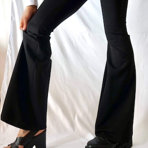Puede incluir: Un pantal&oacute;n negro acampanado con una abertura de pierna ancha. El pantal&oacute;n est&aacute; hecho de una tela suave y el&aacute;stica, perfecto para un look casual.