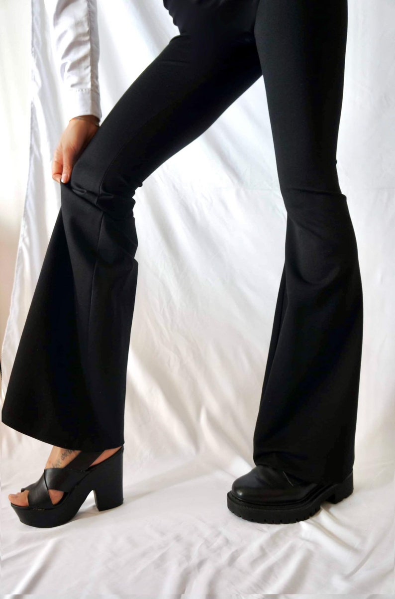 Puede incluir: Un pantal&oacute;n negro acampanado con una abertura de pierna ancha. El pantal&oacute;n est&aacute; hecho de una tela suave y el&aacute;stica, perfecto para un look casual.