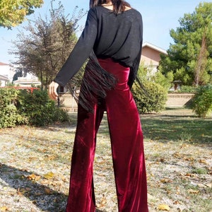 May include: A pair of wide-leg pants in a deep burgundy velvet fabric. The pants have a high waist and a flowing silhouette.