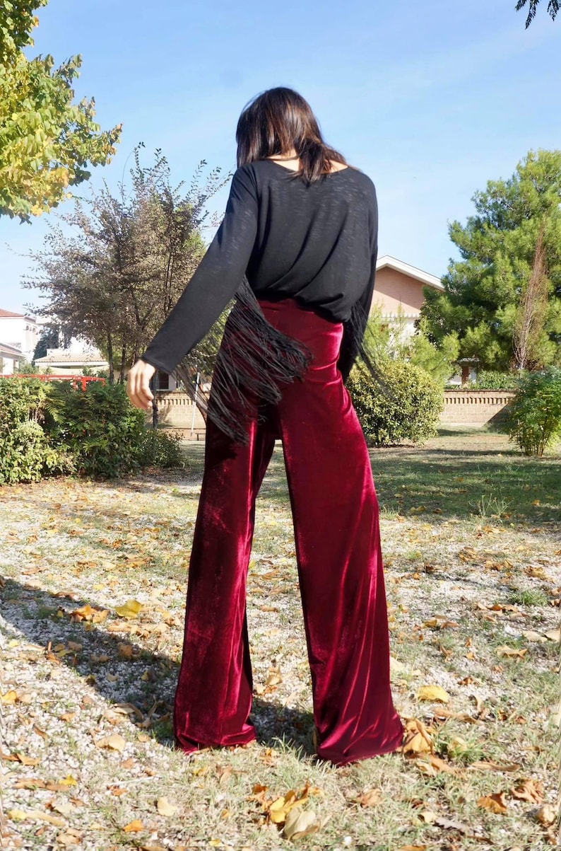 May include: A pair of wide-leg pants in a deep burgundy velvet fabric. The pants have a high waist and a flowing silhouette.