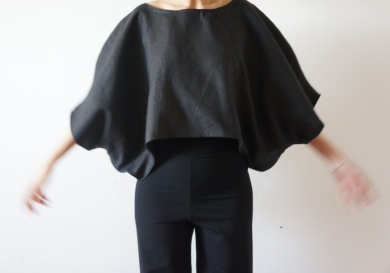 May include: A black linen top with a wide, flowing silhouette. The top has a relaxed fit and a cropped length.