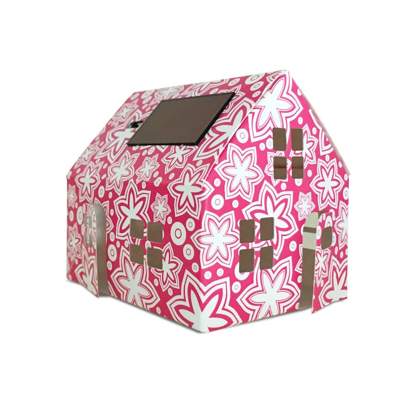 May include: A pink cardboard house with a white floral pattern and a small solar panel on the roof. The house has cut-out windows and a door.
