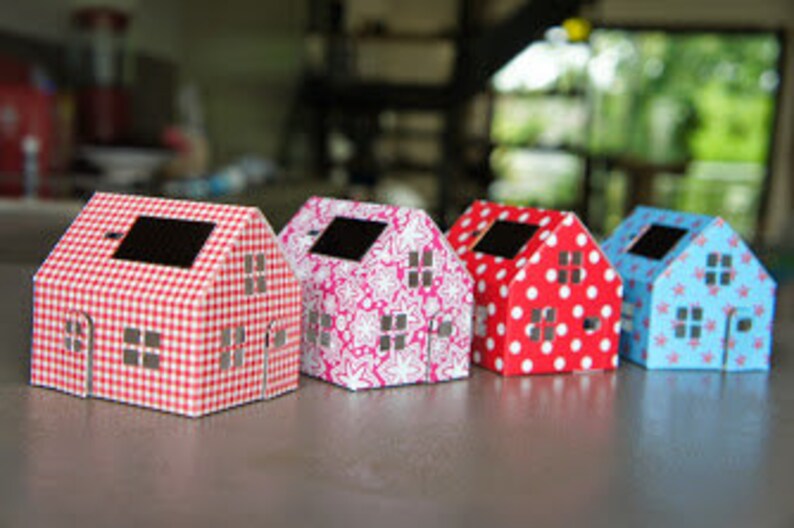May include: Four miniature paper houses with different patterned designs. The houses are red, pink, blue, and white with gingham, floral, polka dot, and star patterns.