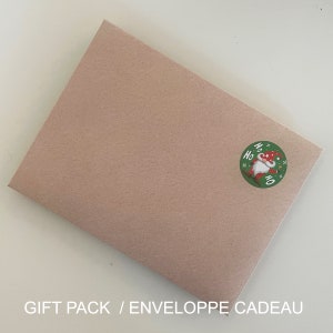 May include: A brown paper gift envelope with a round green sticker featuring a cartoon gnome with a red hat and the words "Ho Ho Ho" in white.