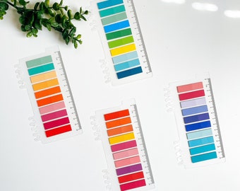 May include: Three sets of colorful sticky notes with different color gradients. Each set has 10 notes in a clear plastic holder with a hole for hanging.