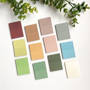 May include: A set of 12 double-sided sticky notes in various colors, including red, orange, yellow, green, blue, and pink. The notes are arranged in a grid pattern on a white surface.