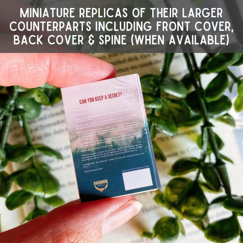 May include: A miniature book replica titled Can You Keep a Secret? featuring a forest landscape graphic on the cover, dark blue and pink text, and a small white square at the bottom. The cover includes the Ravenhood text and logo.