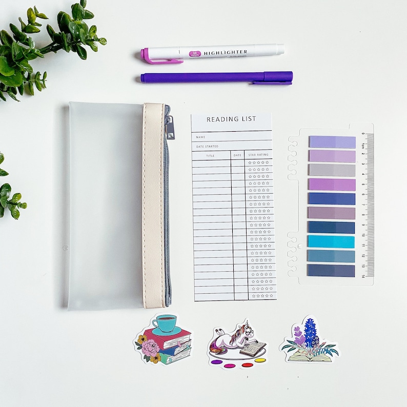 May include: A white reading list tracker with columns for book title, date started, and star rating. The tracker has a clear plastic cover and a set of colorful sticky notes. There are also three stickers of a unicorn reading a book, a cup of coffee with a stack of books, and a book with flowers.
