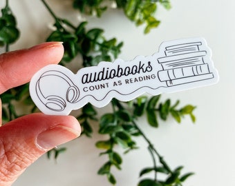 May include: White sticker with a black outline of headphones and a stack of books. The text reads "audiobooks count as reading".