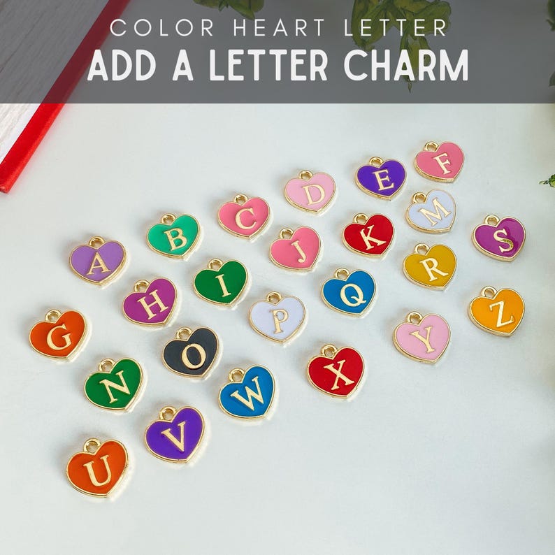 May include: A collection of heart-shaped metal charms, each featuring a gold-colored letter from A to Z. The charms are finished in various vibrant enamel colors including red, blue, green, purple, pink, orange, yellow, and black, with a small loop.