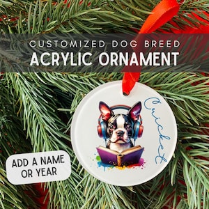 May include: A circular acrylic Christmas ornament with a Boston Terrier wearing headphones and reading a book. Text reads "Customized Dog Breed Acrylic Ornament" and "Add a Name or Year". A red ribbon is attached for hanging.