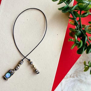 May include: A black cord bookmark with a silver owl charm and beads. The owl has a blue and white eye.