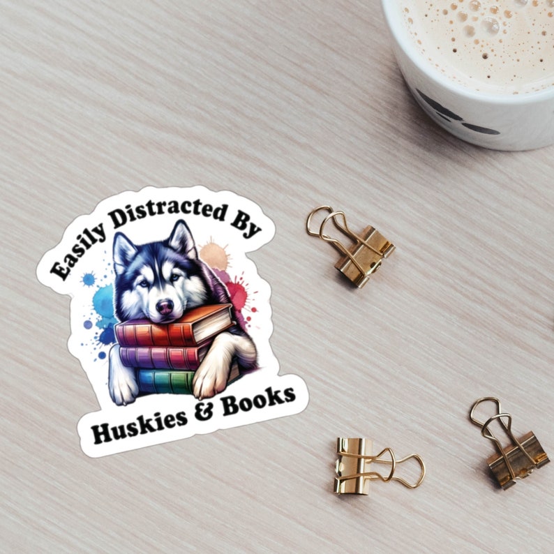 May include: A sticker with a husky dog holding a stack of books. The sticker says "Easily Distracted By Huskies & Books".