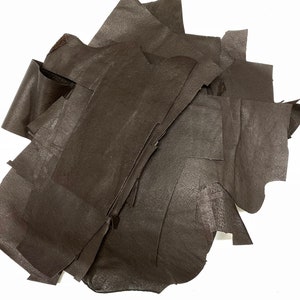 May include: A pile of brown leather scraps. The leather is soft and supple, and it has a natural grain.