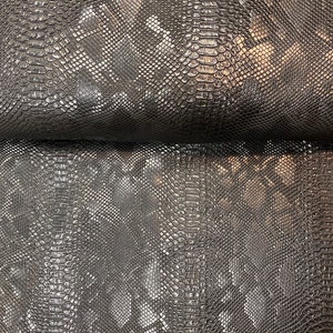 May include: Black faux snakeskin fabric with a textured, embossed pattern. The fabric has a slight sheen.