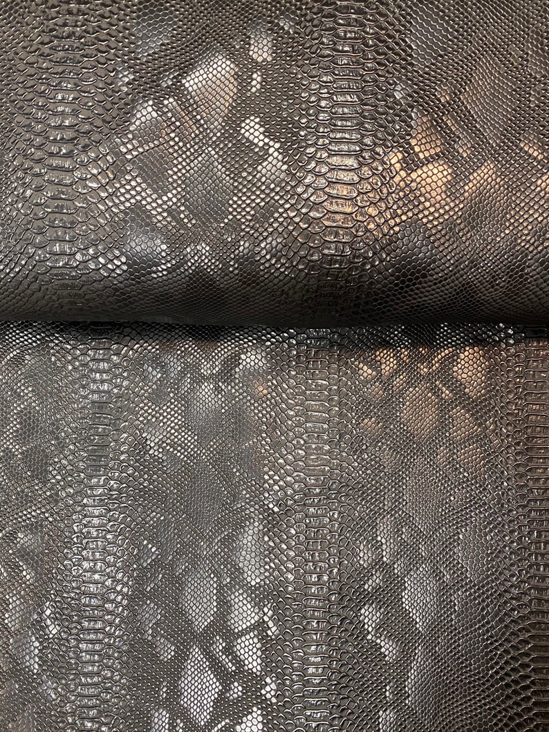 May include: Black faux snakeskin fabric with a textured, embossed pattern. The fabric has a slight sheen.