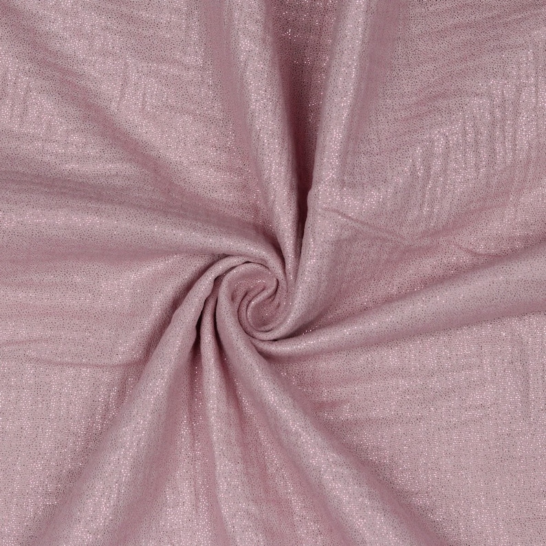 May include: A close-up of a soft, pink fabric with a subtle shimmer. The fabric is folded and draped, showcasing its texture and drape.