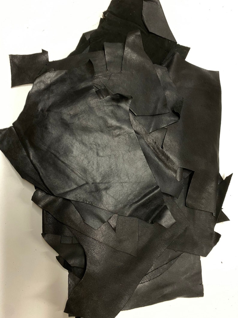 May include: A pile of black leather scraps. The leather is cut into various shapes and sizes.