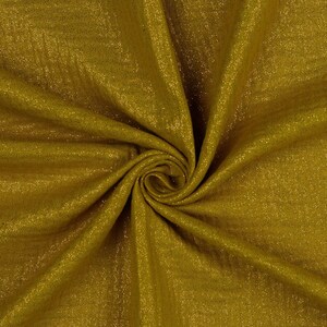 May include: A close-up of a gold fabric with a sparkly texture. The fabric is folded and draped, creating a soft and luxurious look.