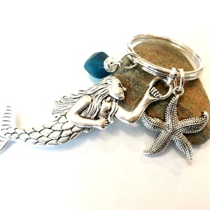May include: Silver mermaid keychain with a blue glass bead, a silver starfish charm, and a silver key ring.