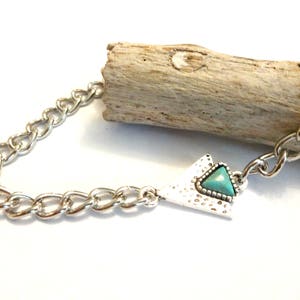 May include: A silver chain necklace with a triangular pendant featuring a turquoise stone.