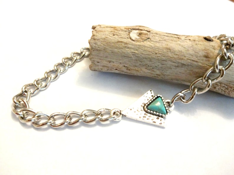 May include: A silver chain necklace with a triangular pendant featuring a turquoise stone.