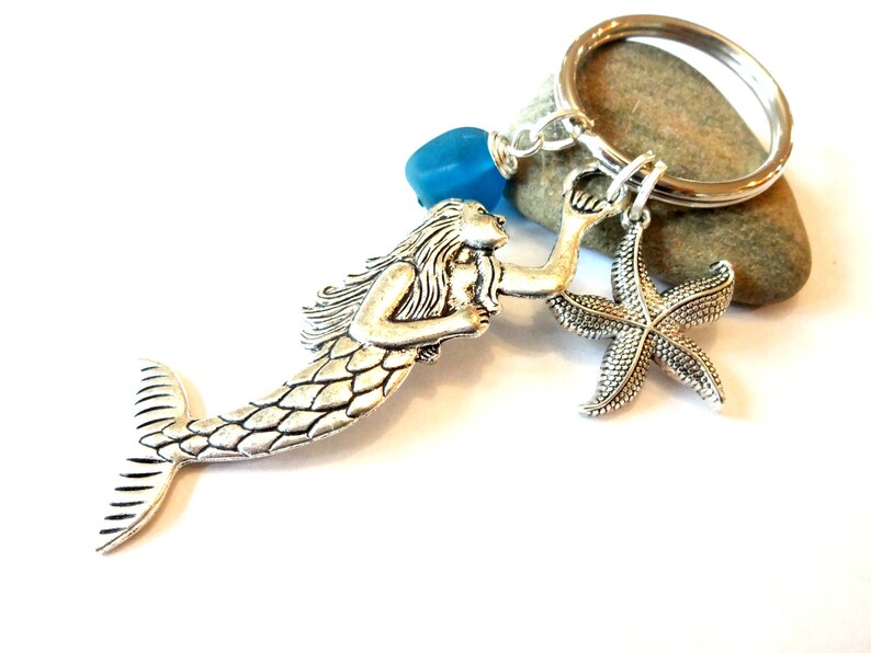 May include: Silver mermaid charm with a blue glass bead and a silver starfish charm attached to a silver key ring.