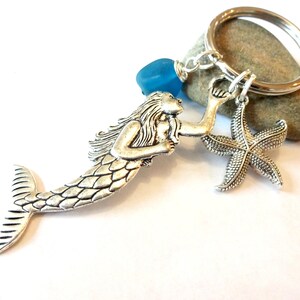 May include: Silver mermaid keychain with a blue glass bead and a silver starfish charm.