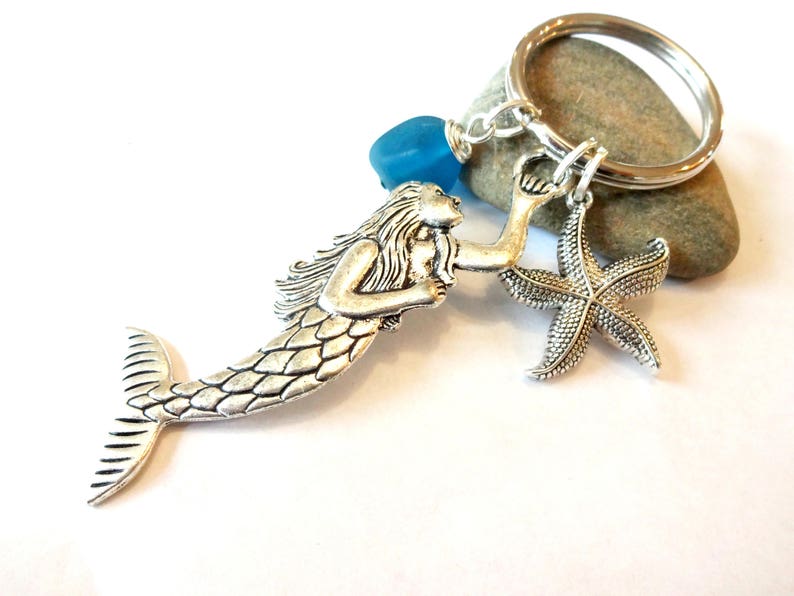 May include: Silver mermaid keychain with a blue glass bead and a silver starfish charm.
