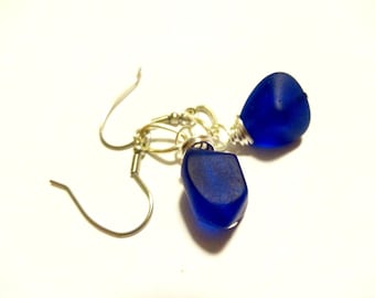 May include: A pair of earrings with cobalt blue glass teardrop-shaped beads and silver wire accents.
