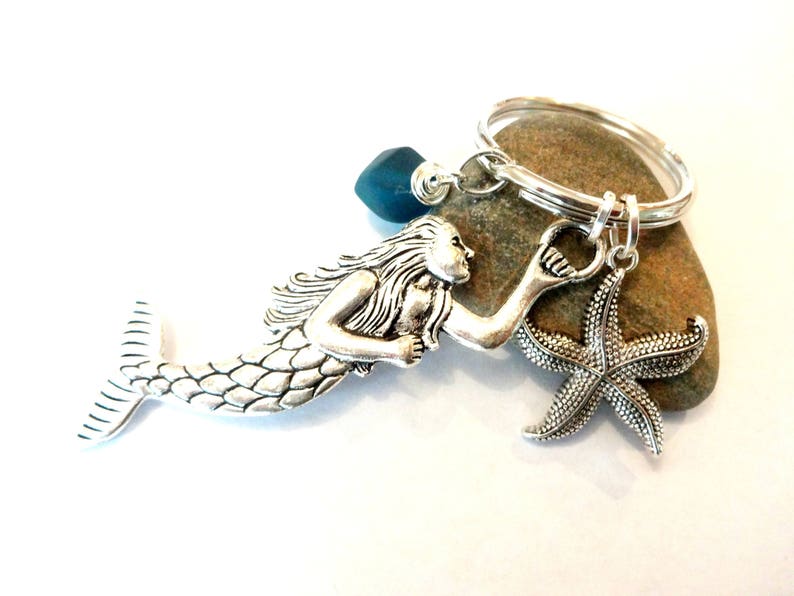 May include: Silver mermaid keychain with a blue glass bead, a silver starfish charm, and a silver key ring.