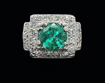 May include: A silver ring with a large green emerald gemstone surrounded by smaller clear gemstones.
