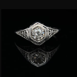 Può includere: Un anello d'argento con un delicato design a filigrana e un singolo diamante rotondo al centro.