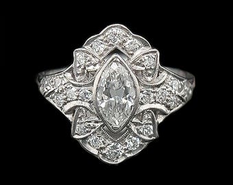 Könnte beinhalten: Ein silberner Ring mit einem Marquise-Diamanten, der in einem floralen Design gefasst ist. Der Ring ist mit kleineren Diamanten um den Mittelteil verziert.
