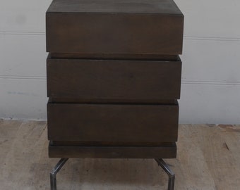 May include: A dark brown wooden chest of drawers with three drawers and metal legs.