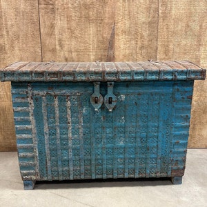 May include: A vintage blue wooden chest with a decorative woven pattern and metal hinges. The chest has a distressed finish and is sitting on a wooden floor.