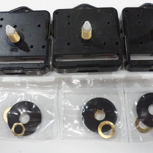 May include: Three black clock movements with gold-colored hands and a white plastic knob. Three small plastic bags each contain a black washer, a gold-colored washer, and a gold-colored nut.
