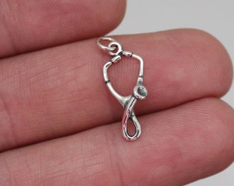 May include: Silver stethoscope charm pendant. The charm is in the shape of a stethoscope with a silver finish.